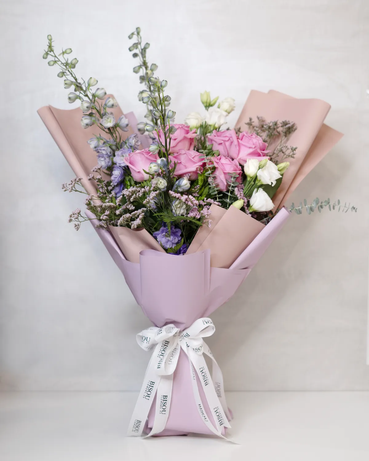 Delphinium Dreams bouquet of pink roses, delphinium, white lisianthus with fillers of pink limonium